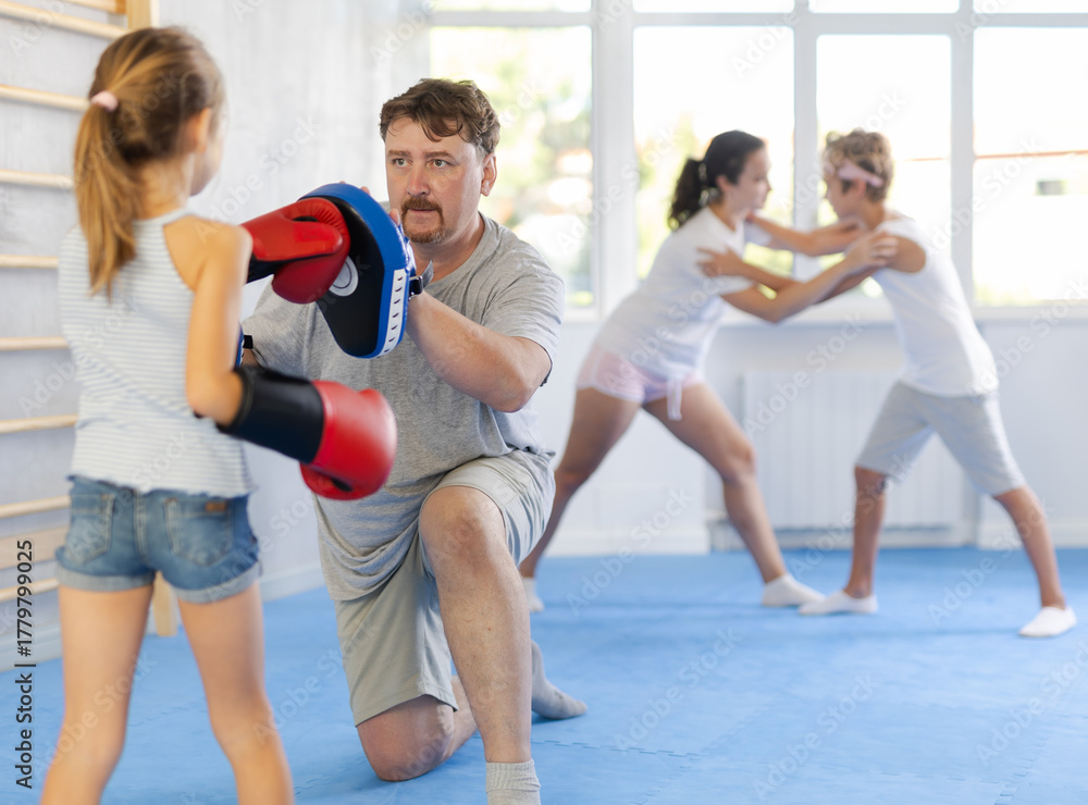Fototapeta premium Father and daughter wearing boxing gloves practice boxing technique in gym