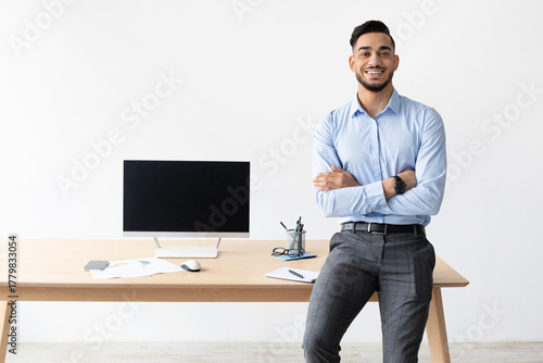 Ταπετσαρία A smiling bearded business man leans on a table in his home office, confidently displaying a laptop with a black screen