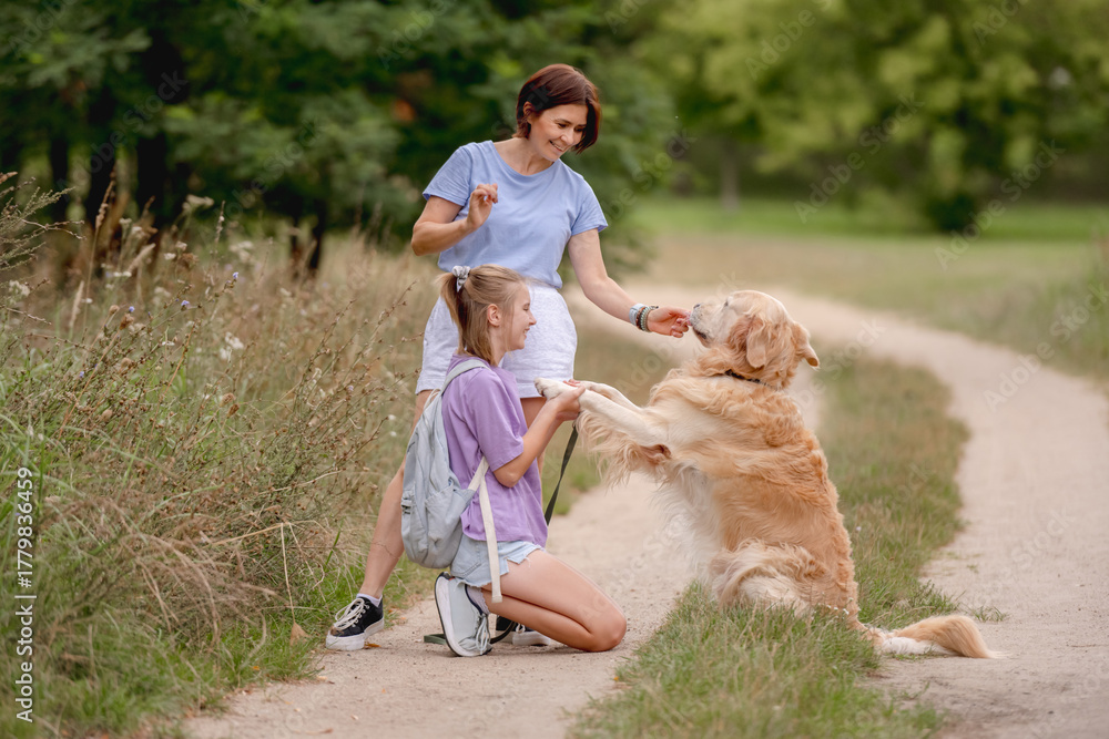 Fototapeta premium Mom, Daughter, And Golden Retriever On A Summer Walk
