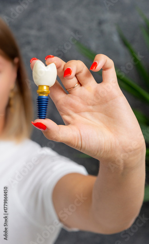 A person holds a model of a dental implant