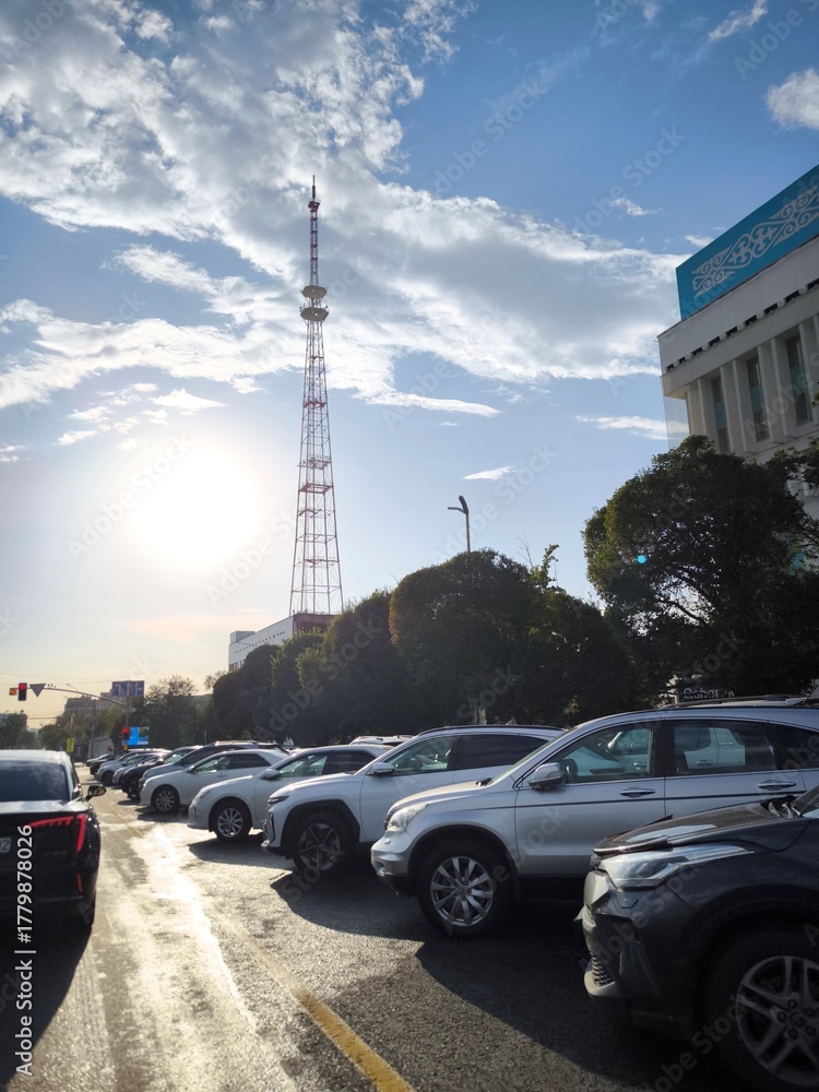 Fototapeta premium The Koktobe TV tower against the backdrop of a city street with parked cars in Almaty.