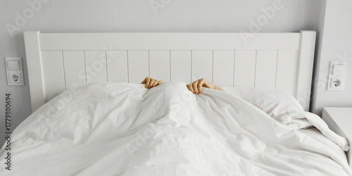 Healthy sleep, woman lying in bed under white blanket hiding her face in bedroom at home