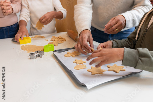 Diverse family pressing star and tree cookie cutters into dough on white countertop in home kitchen