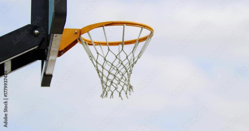 Fototapeta premium Showing basketball hoop with orange rim and white net at outdoor court left, copy space