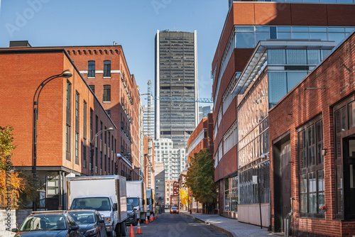 Downtown Montreal street view leading toward corporate towers and the skyline. Brick buildings, trucks and a crane frame the high rise core, highlighting the city's economic hub in Quebec, Canada.