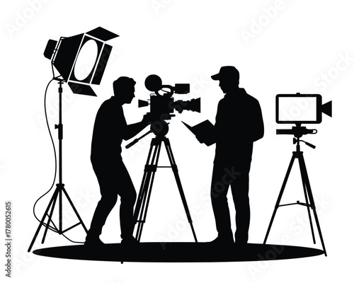 Filmmakers operating camera and tablet with lighting silhouette tripod