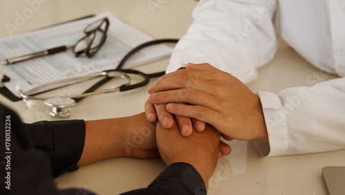 Doctor comforting and supporting patient by holding hands during medical consultation showing care empathy and trust in healthcare.