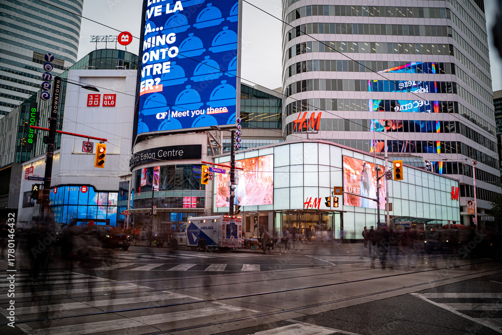 Fototapeta premium View of Sankofa Square (Yonge-Dundas) with motion blur of people in Toronto. Toronto, Canada - October 17, 2025.