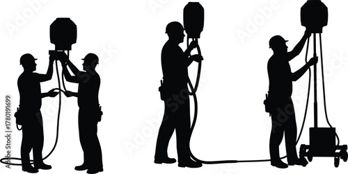 Construction workers adjusting and setting up industrial lighting equipment for nighttime site work and maintenance with safety helmets and tools