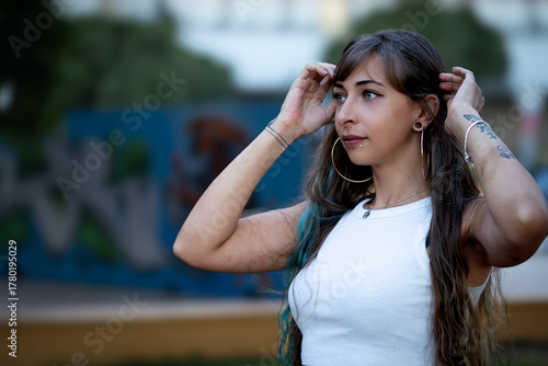 Young woman adjusting hair urban skatepark background