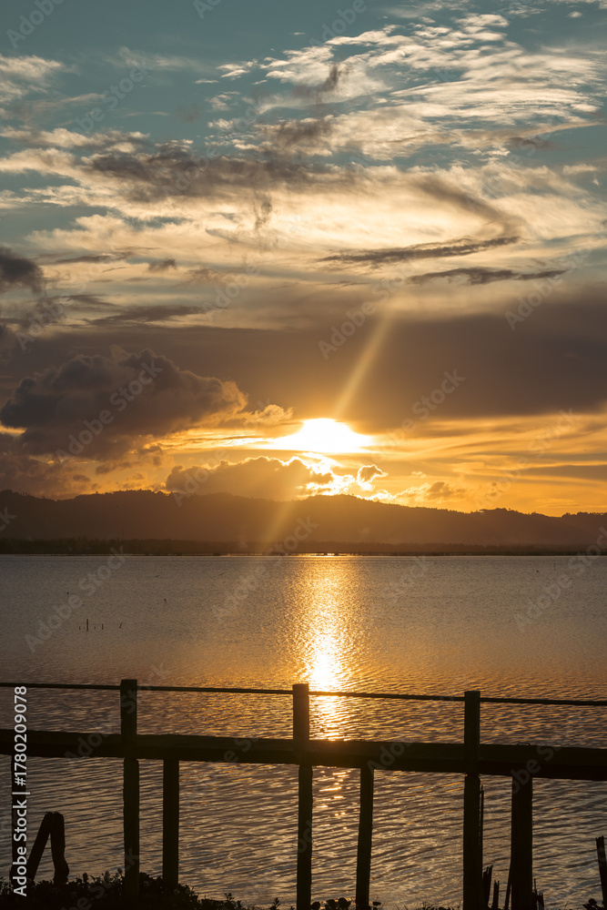 Fototapeta premium Scenic Sunset Over Water and Distant Mountains