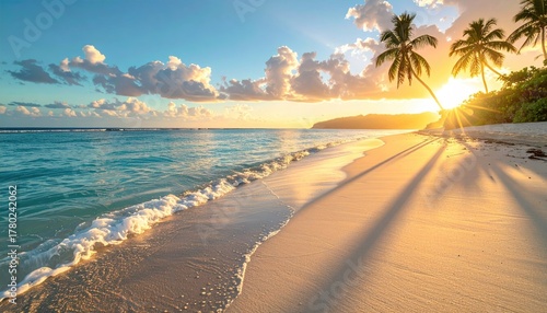 Fototapeta Naklejka Na Ścianę i Meble -  Warm golden sunset casting long shadows across a sandy beach with gentle turquoise waves lapping the shore and palm trees silhouetted against the vibrant sky