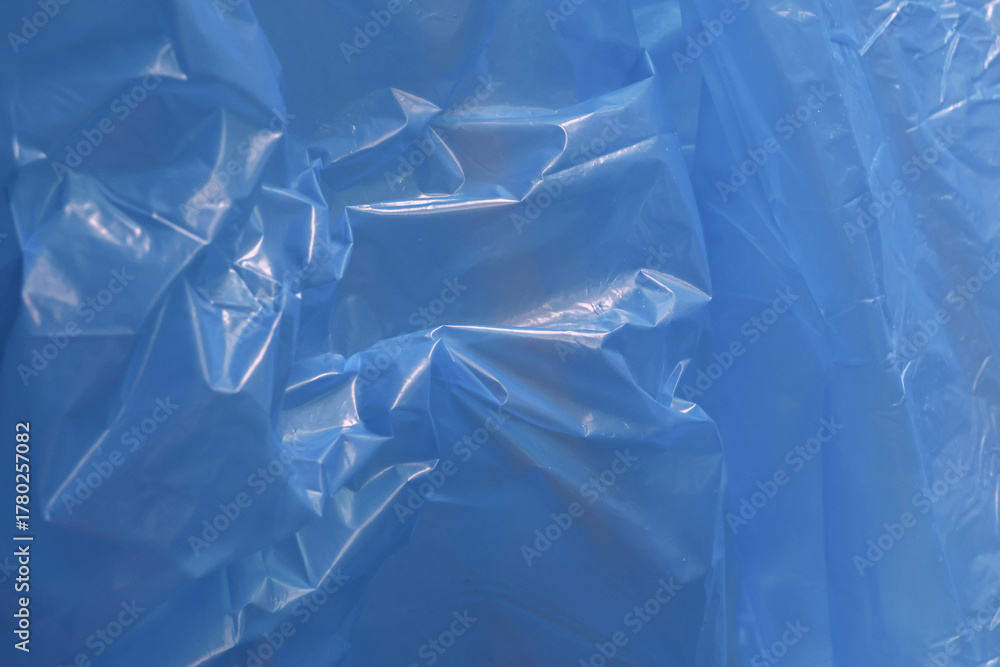 Obraz premium Abstract blue plastic background with crumpled and wrinkled texture. This shiny sheet surface provides detailed and interesting pattern for various design concepts