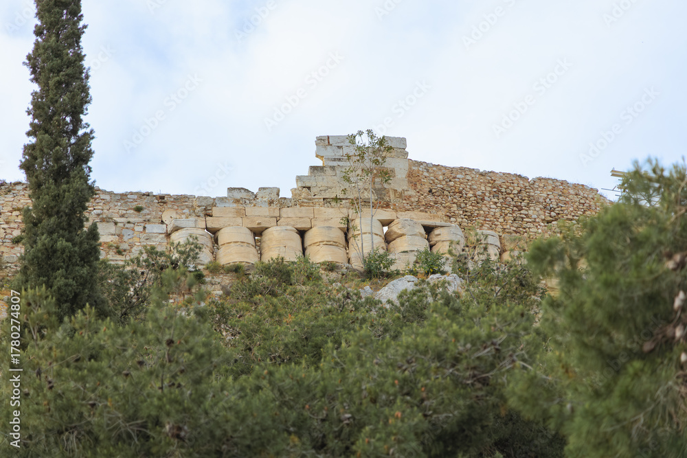 Fototapeta premium Ancient marble ruins of the Acropolis in Athens, Greece. Historic temple remains surrounded by greenery. Archaeology and classical heritage concept