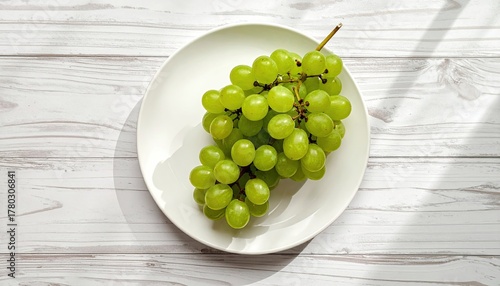 Fresh Green Grapes on a White Plate With Natural Sunlight and Shadow Patterns on a White Wooden Table Surface