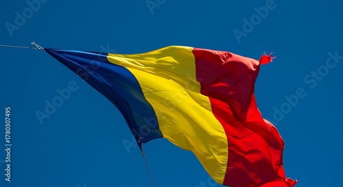 Romanian flag waving proudly against a clear blue sky, symbolizing national pride and a bright future on a sunny day, evoking a sense of patriotism.