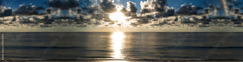Obraz premium Sunrise over ocean horizon panoramic. Dawn sky above sea banner. Beautiful seascape with sunset. Morning sun over calm water. Peaceful sunrise ocean view. Scenic ocean sunrise. Seascape with clouds.