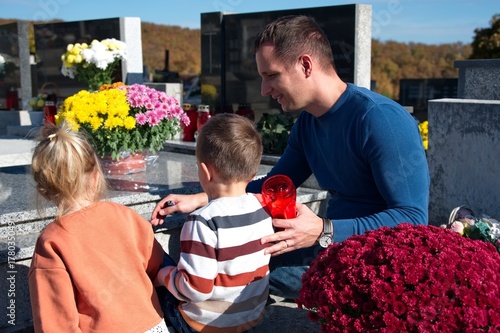 Father and little children lighting a candle at the grave