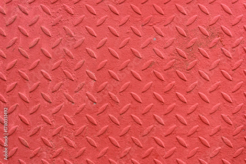 A close-up of an old corrugated sheet of metal with lentil-shaped protrusions. The surface has been coated with fresh red paint.
