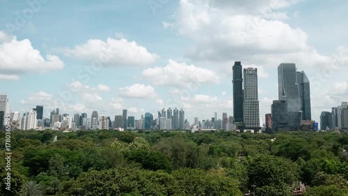 Timelapse of clouds over skyscrapers and dense trees in Lumphini Park  in Bangkok, Thailand