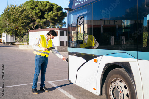 Fotografie Quality supervisor performing a daily inspection on a public electric bus, ensur