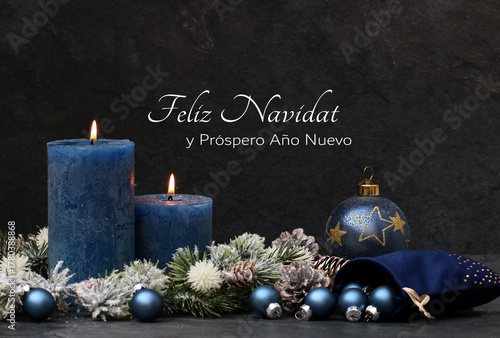 Tarjeta navideña: Velas azules encendidas con ramas de abeto y adornos navideños sobre un fondo gris oscuro. Con el texto 