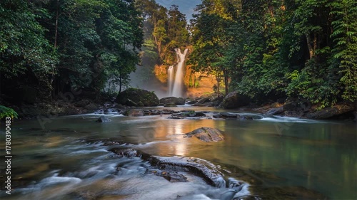 Tropical river waterfall lush forest scene, sunlight reflecting on water, surrounded by dense green trees, tranquil and natural landscape perfect for relaxation.