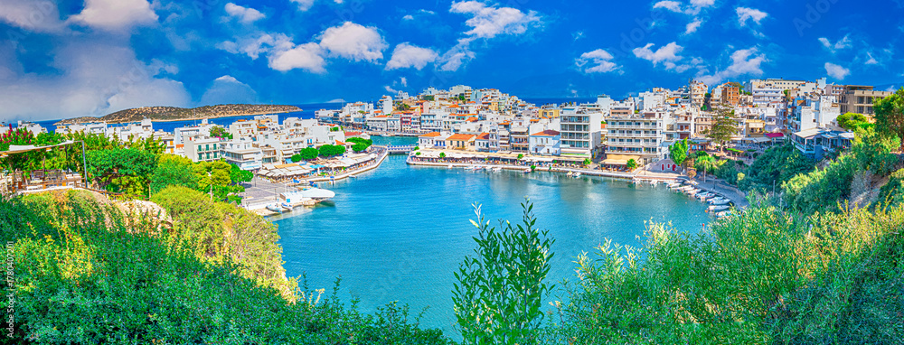 Fototapeta premium Travel Concepts. Picturesque View of Colorful Agios Nikolaos Village with Prodigious Voulismeni Lake Taken from View Point as Famous Travel Tourist Destination of Crete Island in Greece. Panorama Imag