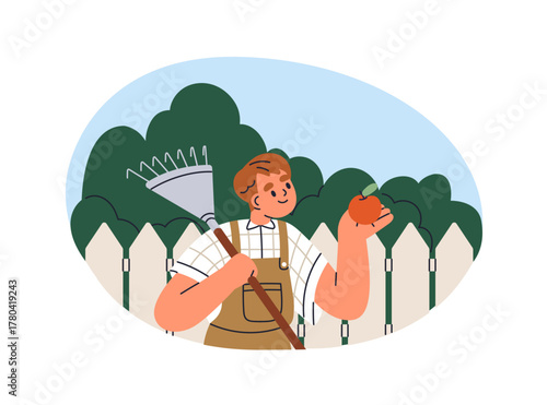 Boy kid with rake tool and apple in hand. Child farmer in garden, orchard dur...