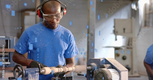 Bilde på lerret Operating lathe, mature Black man shaping spindle with shavings in shop, wearing