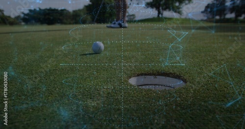 Fotografie Displaying white golf ball resting near cup on putting green, with digital overl