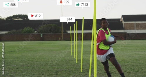 Running teen in neon bib holding white-blue ball on pitch, with yellow poles overlays, copy space