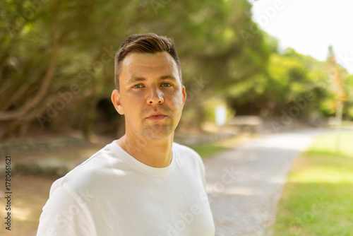 Young adult man posing confidently in a lush park