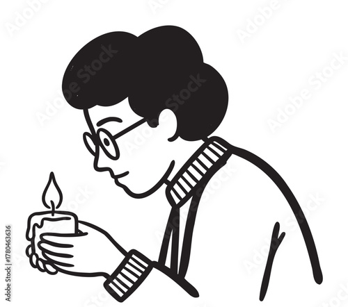 A young adult caucasian male with curly hair and glasses holds a flaming candle with both hands, wearing a sweater, in a contemplative side profile.