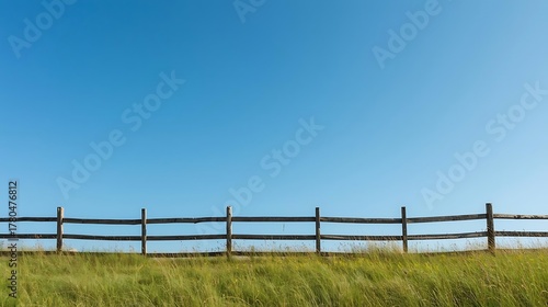 Fototapeta Naklejka Na Ścianę i Meble -  rustic fence across a meadow with clean blue sky