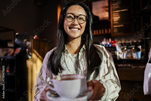 Smiling barista serving coffee at cafe counter indoors