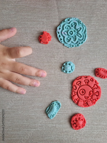 Covid and other respiratory virus molecules made of plasticine. Little toddler education moment in a playful mode. Bacteria made of playdough and kids' hands over the table. 