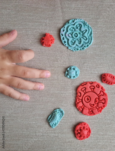 Covid and other respiratory virus molecules made of plasticine. Little toddler education moment in a playful mode. Bacteria made of playdough and kids' hands over the table. 