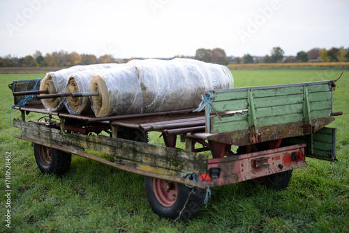 Gummiwagen auf einer Ackerbaufläche der Landwirtschaft einer Herbstlandschaft im faden, natürlichen Morgenlicht.