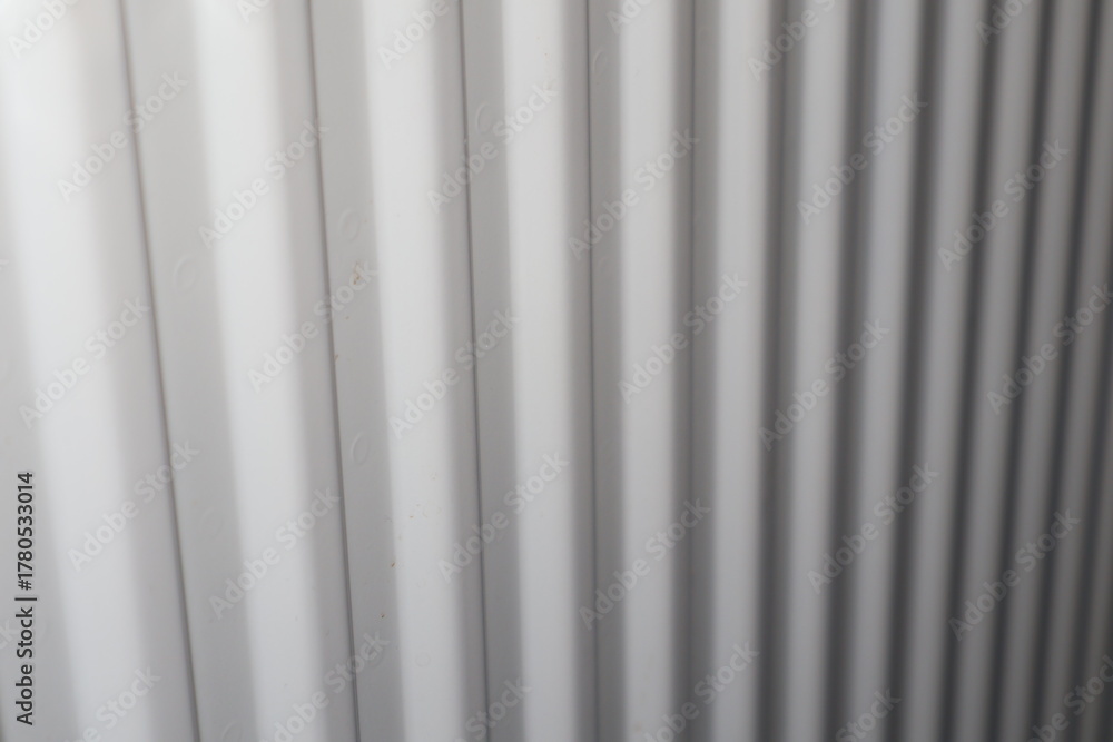 Obraz premium White radiator heating panel with vertical fins, close-up of indoor heating element in home interior