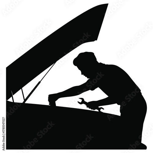 Silhouette of a mechanic working on a car engine under an open hood