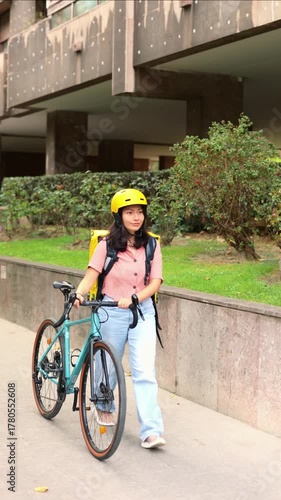 vertical Asian delivery courier woman walking with her bicycle