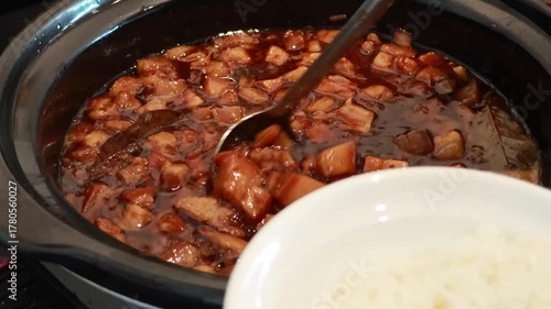 Stirring and pouring braised pork belly meat over cooked rice.