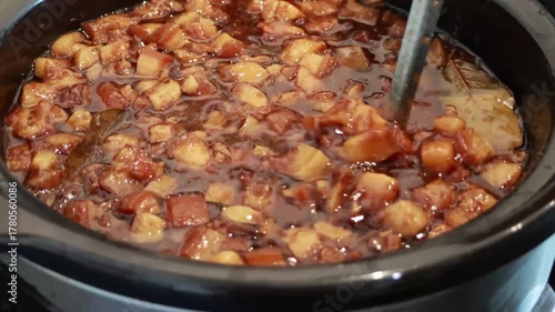 Stirring and pouring braised pork belly meat over cooked rice.