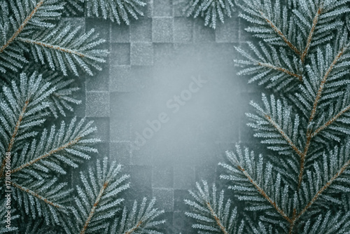 Frosted pine branches surround a blank space on a textured background for winter decoration