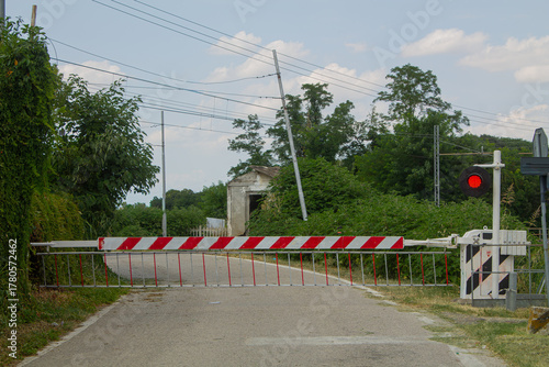 Obraz na plátně Rural railway crossing with barrier and red signal light — transport safety and