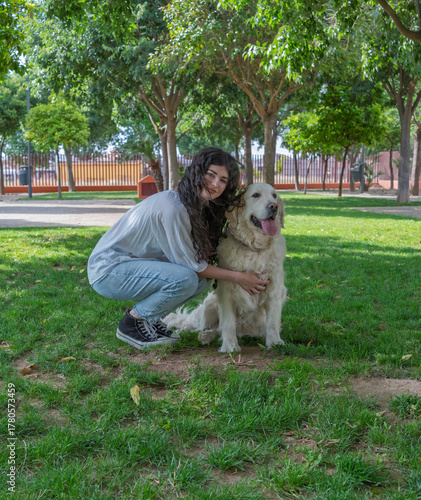 Young woman hugging her golden retriever in a park