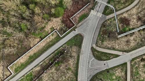 Aerial top-down video of road intersection in Kohtla-Jarve (Estonian - Kohtla-Järve), Estonia. Drone slowly moving forward above roads, crosswalks, pipelines, and greenery. 