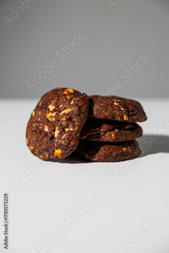 A stack of rich double chocolate cookies with nut chunks arranged on a white surface, showcasing texture and contrast. No visible branding