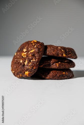 A stack of rich double chocolate cookies with nut chunks arranged on a white surface, showcasing texture and contrast. No visible branding